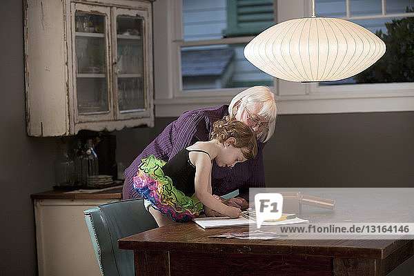 Großmutter und Enkelin stehen am Tisch und zeichnen