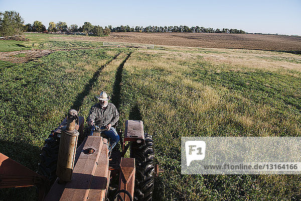 High angle view of senior male farmer driving tractor in field  Plattsburg  Missouri  USA