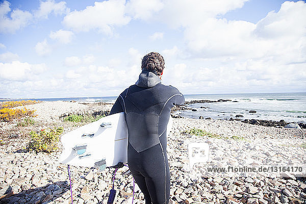 Male surfer carrying surfboard on beach  Gloucester  Massachusetts  USA