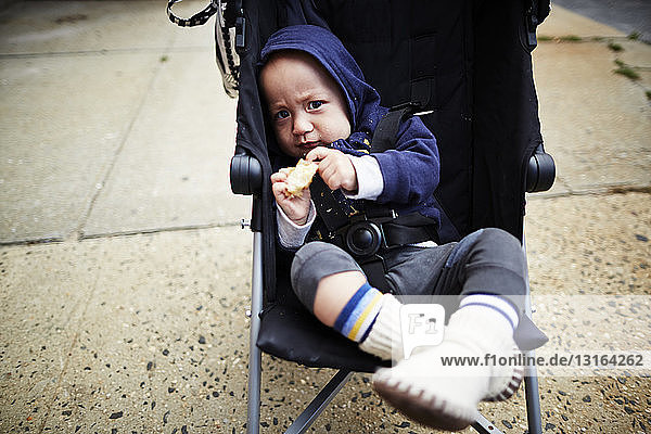 Baby boy holding cookie in carriage