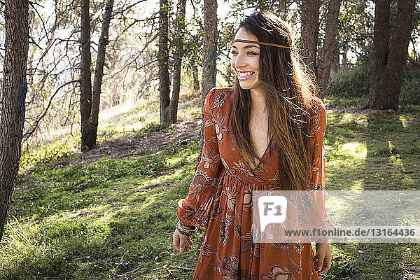 Portrait of young woman wearing dress in forest  smiling
