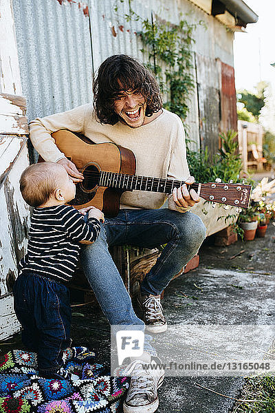 Vater unterhält Sohn mit Gitarre