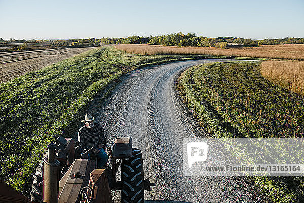 High angle view of senior male farmer driving tractor on rural road  Plattsburg  Missouri  USA