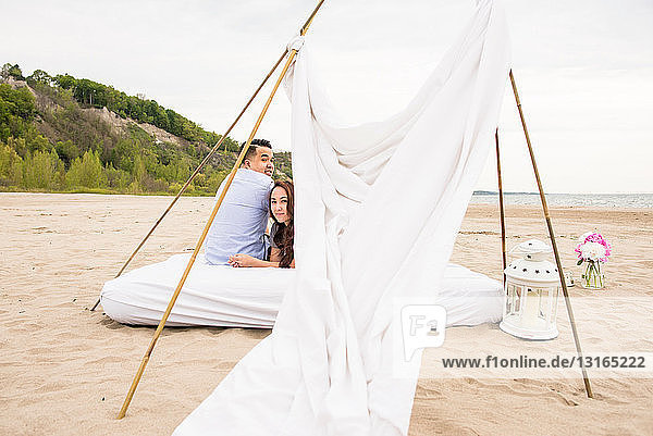 Junges Paar unter Baldachin am Strand
