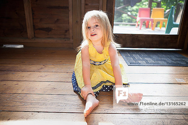 Weibliches Kleinkind auf Holzboden sitzend