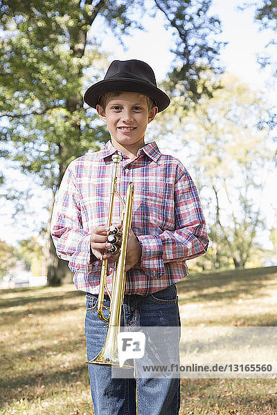 Bildnis eines Jungen mit einem Trilby, der eine Trompete in den Wäldern hält