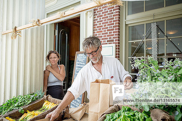 Farmer selling organic food on stall outside store