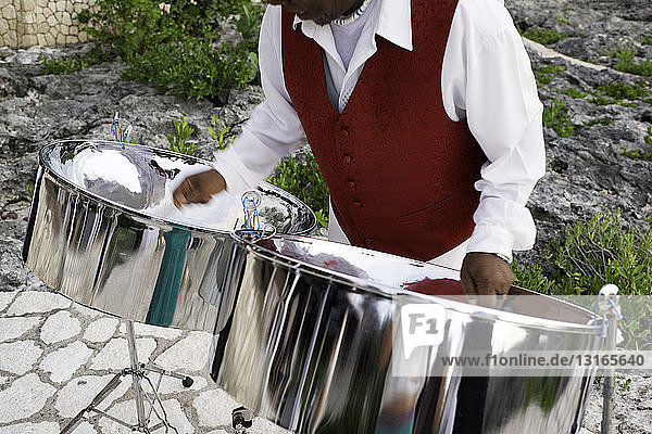 Mature man playing steel drums  mid section