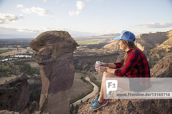 Young woman sitting gazing at view from top of Smith Rock  Oregon  USA