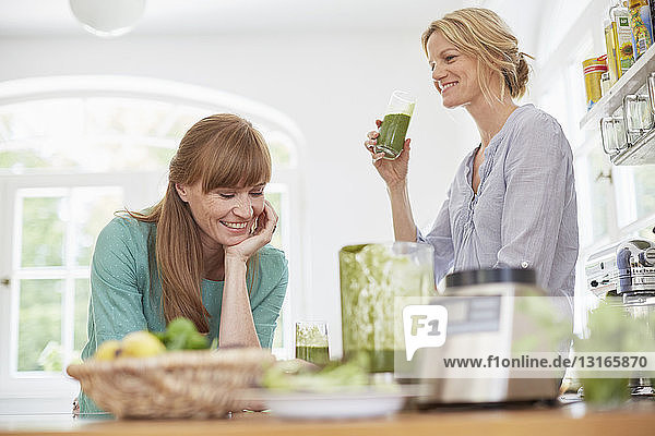 Frauen trinken grünen veganen Smoothie in der Küche