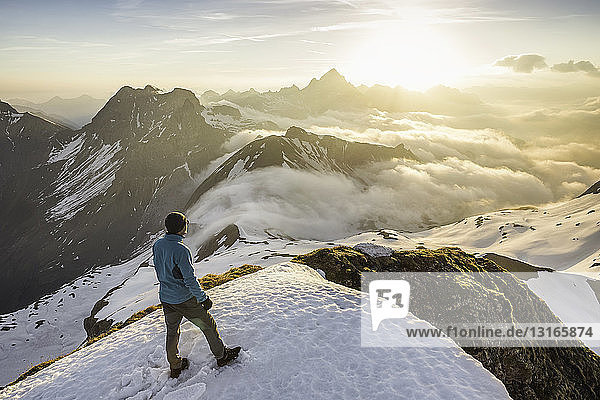 Young male mountain trekker looking at view of clouds Bavarian Alps Oberstdorf Bavaria Germany