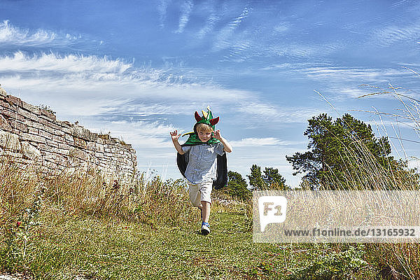 Boy wearing green cape running along grass  Eggegrund  Sweden