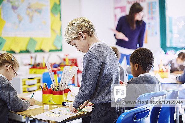 Jungen und Mädchen beim Zeichnen am Schreibtisch in der Grundschule