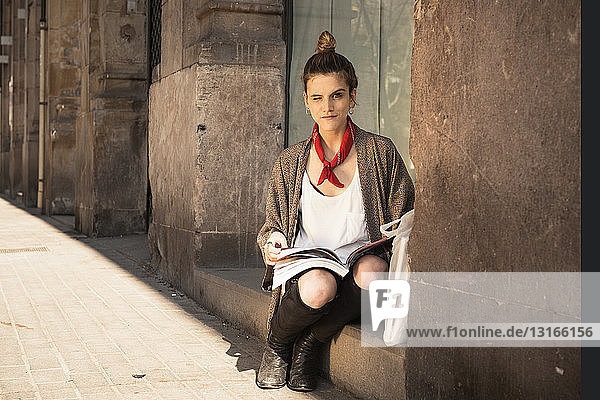 Junge Frau liest Zeitschrift auf Schritt und Tritt  El Born  Barcelona  Spanien