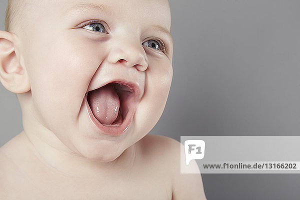 Cropped studio portrait of smiling baby boy with mouth open