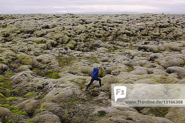 Seitenansicht einer mittleren erwachsenen Frau  die über eine hügelige Vulkanlandschaft läuft  Island