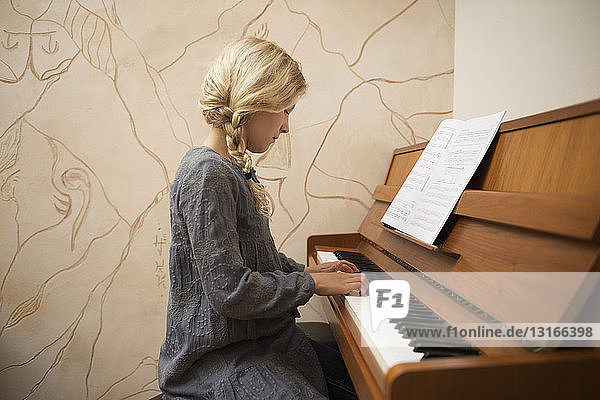 Portrait of girl playing the piano in dining room