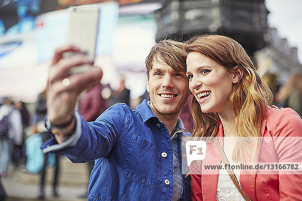 Touristisches Ehepaar beim Selfie auf dem Smartphone am Piccadilly Circus  London  Großbritannien