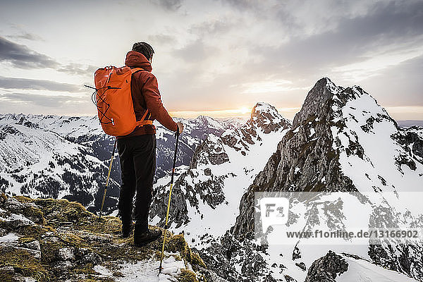 Rear view of hiker looking at snow capped mountain range  Kellenspitze  Tannheim mountains  Tyrol  Austria