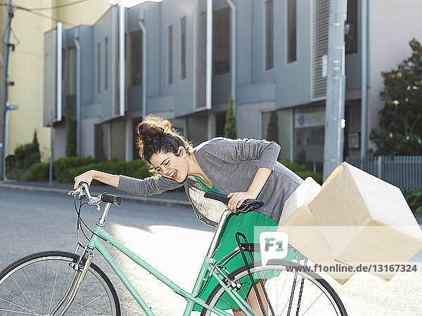 Junge Frau mit Fahrrad und fallenden Pappkartons