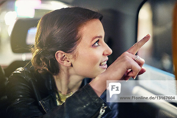 Junge Frau in Taxi  die aus dem Fenster zeigt