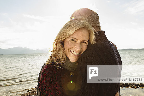 Mature couple beside lake  hugging  smiling