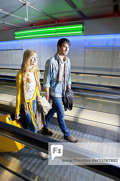 Couple on moving walkway in airport
