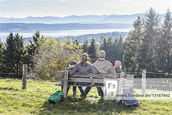 Rear view of family sitting on park bench looking out at view  Tutzing  Bavaria  Germany