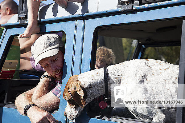 Erwachsener Mann und Hund lehnen sich aus dem Fenster eines Geländewagens  Lake Okareka  Neuseeland