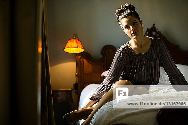 Woman sitting on bed in hotel room