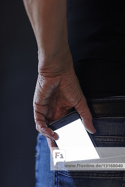 Frau entfernt Smartphone von Hand aus der Gesäßtasche