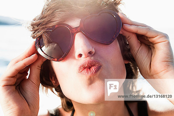 Frau mit Sonnenbrille posiert am Strand