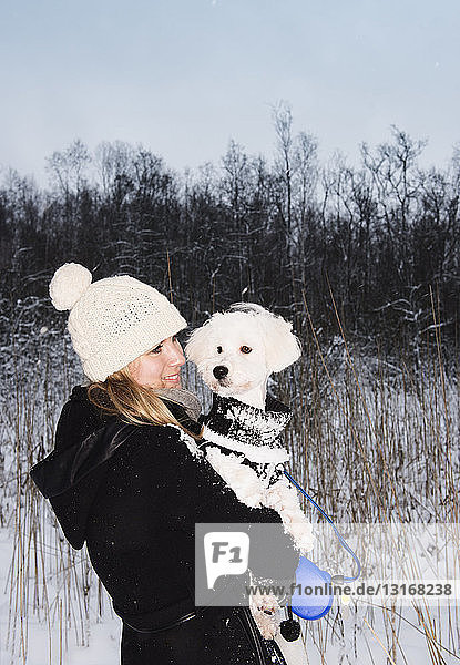Mittlere erwachsene Frau mit Haushund in verschneiter Landschaft