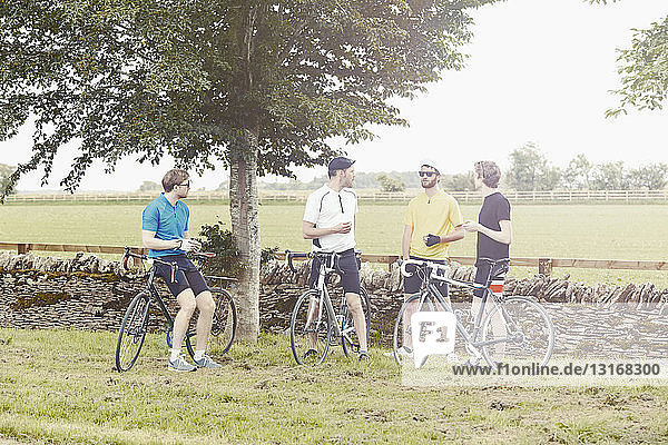 Cyclists standing by stone wall  Cotswolds  UK