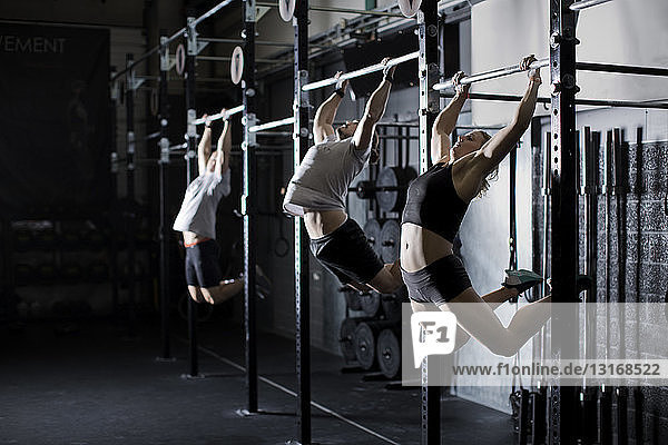 Männliche und weibliche junge Erwachsene trainieren an der Sprossenwand im Fitnessstudio