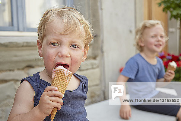Zwei Jungen sitzen draußen und essen Eiscreme