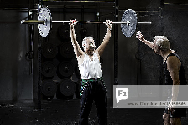 Senior men training with barbell in dark gym