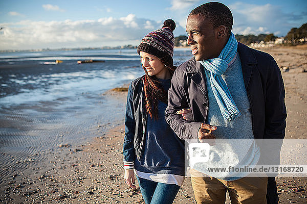 Romantisches junges Paar Arm in Arm am Strand
