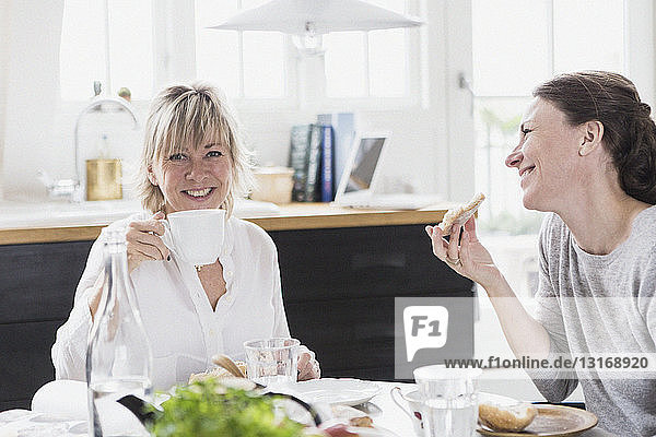 Zwei reife Frauen sitzen am Küchentisch und trinken Tee