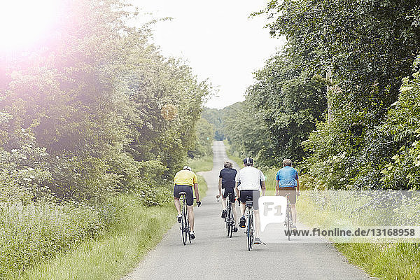 Cyclists riding on leafy countryside road  Cotswolds  UK
