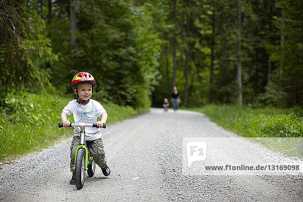 Toddler boy riding bike on dirt path
