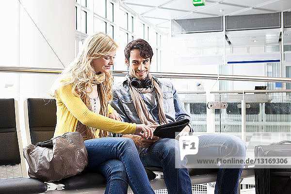 Couple using tablet computer in airport