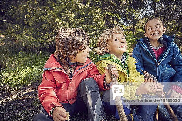 Drei Kinder sitzen zusammen im Wald