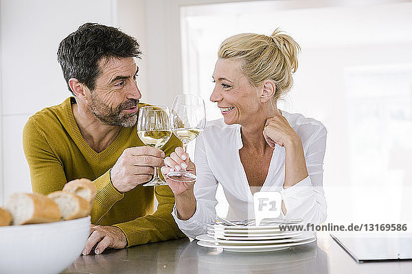 Ein reifes Paar  das an der Küchentheke ein Glas Wein zueinander trinkt