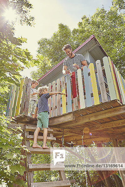 Vater und zwei Söhne malen Baumhaus