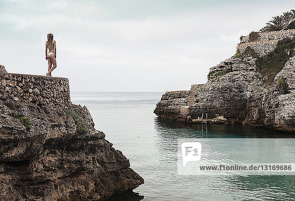 Rückansicht einer jungen Frau im Bikini mit Blick auf Cala en Brut  Menorca  Balearen  Spanien