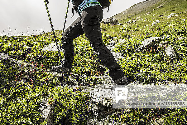 Legs of female hiker hiking through stream  Fil de Cassons  Segnesboden  Graubunden  Switzerland