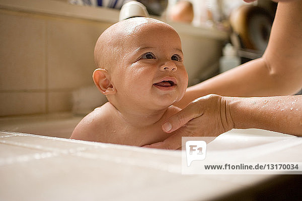 Mutter badet Baby Junge in Küchenspüle