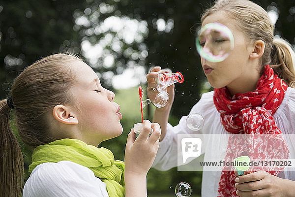 Two sisters blowing bubbles