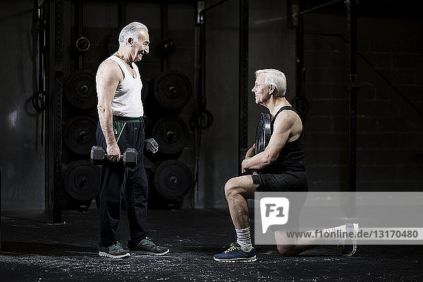 Ältere Männer bereiten sich in dunkler Turnhalle auf das Gewichtheben vor